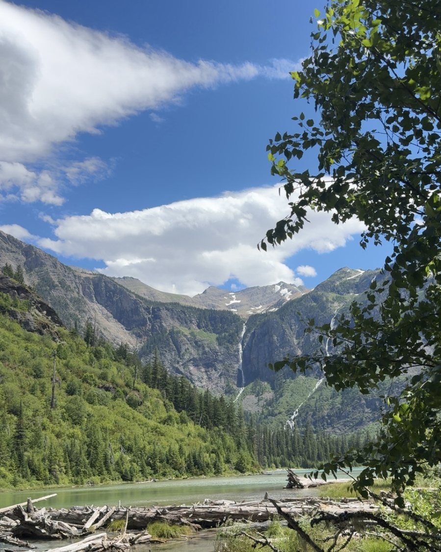 A glacier lake below waterfalls and snowy peaks